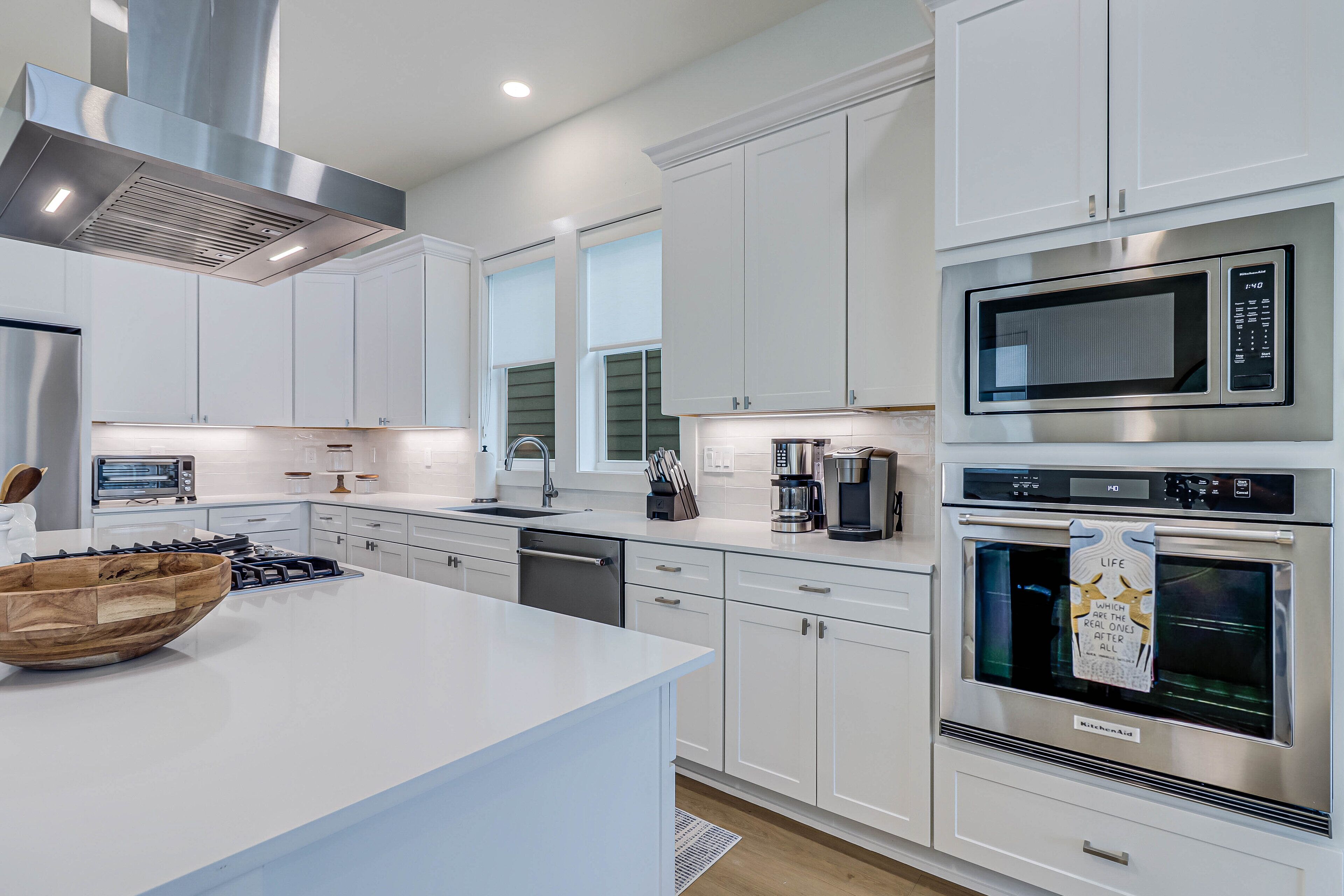 A modern kitchen with white cabinetry, stainless steel appliances, and a large island.