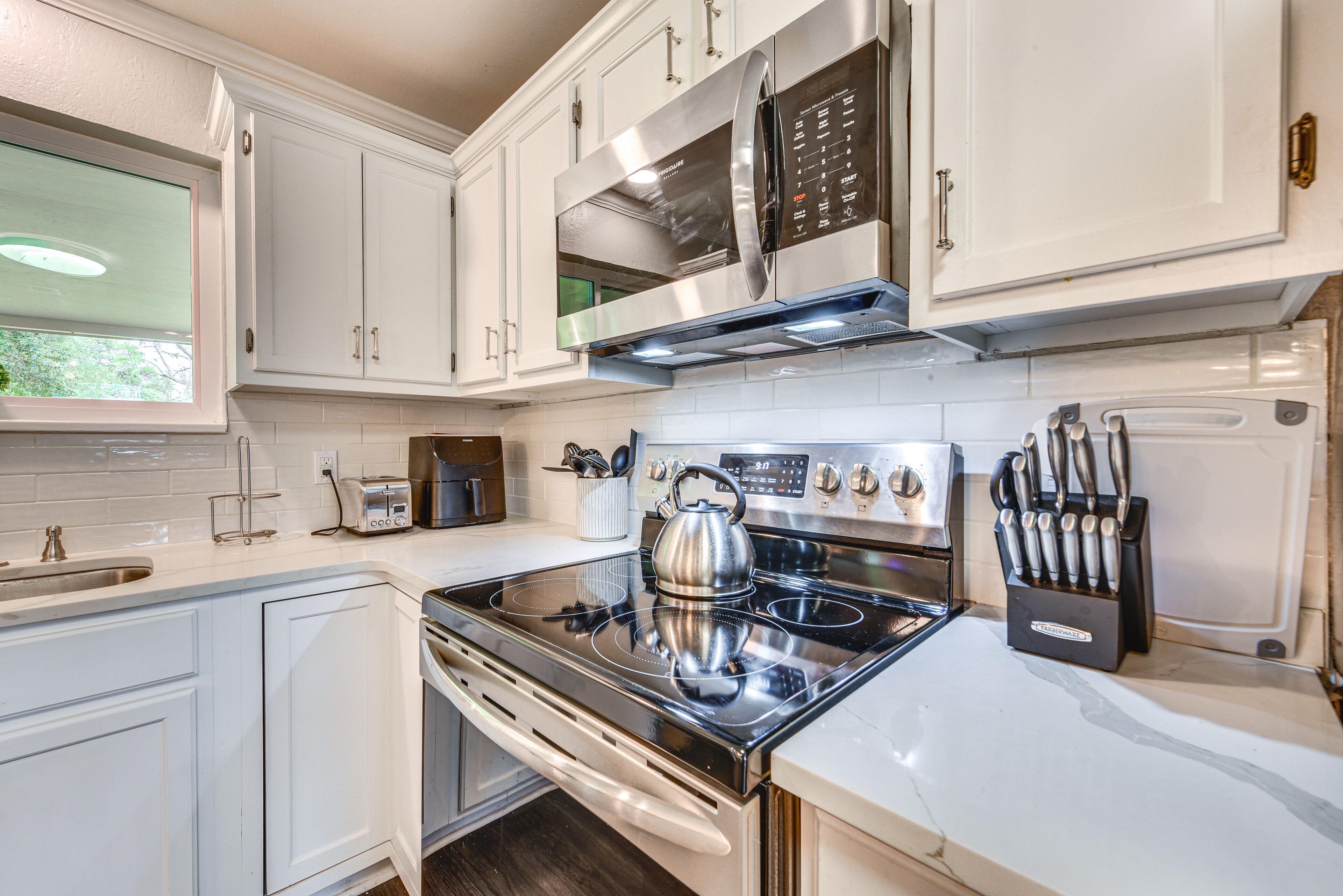 A modern kitchen with white cabinets, stainless steel appliances, and a built-in oven.
