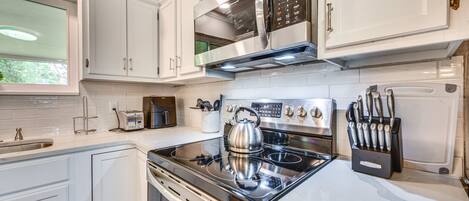 A modern kitchen with white cabinets, stainless steel appliances, and a built-in oven.