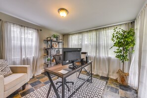 A living room with a sofa, a TV on a stand, a coffee table, a plant, and a bookshelf. - Baton Rouge Home w/ Private Patio: 2 Mi to LSU! (Baton Rouge)
