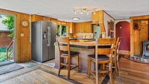 A compact kitchen with wooden cabinets, a refrigerator, and a central island with chairs. - Priest Lake - Escape to the Lake (Nordman)