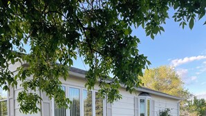 A single-story house with a front porch, a pathway leading to the entrance, and a well-maintained lawn. - Hill Cottage (Park River)