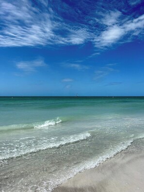 A beach with clear water and a distant boat.