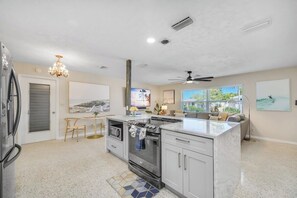 Una cocina moderna con una isla central, horno empotrado y una zona de comedor con una mesa redonda y sillas.
