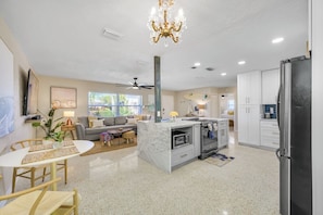 A modern kitchen with a central island, built-in appliances, and a dining area with a table and chairs.