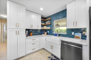 A modern kitchen with white cabinetry, a stainless steel dishwasher, and a blue-tiled backsplash. - 5 Minutes to Madeira Beach • Private Cowboy Pool (Seminole)