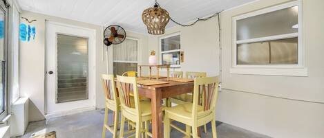 Un comedor con una mesa de madera y sillas amarillas, un ventilador y una lámpara decorativa.