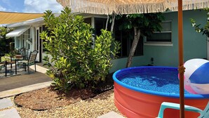 Um quintal com piscina, móveis de varanda e um guarda-sol decorativo.
