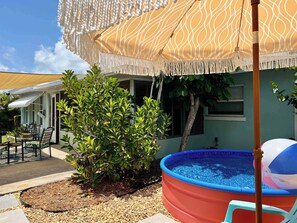 A backyard with a swimming pool, patio furniture, and a decorative umbrella. - 5 Minutes to Madeira Beach • Private Cowboy Pool (Seminole)