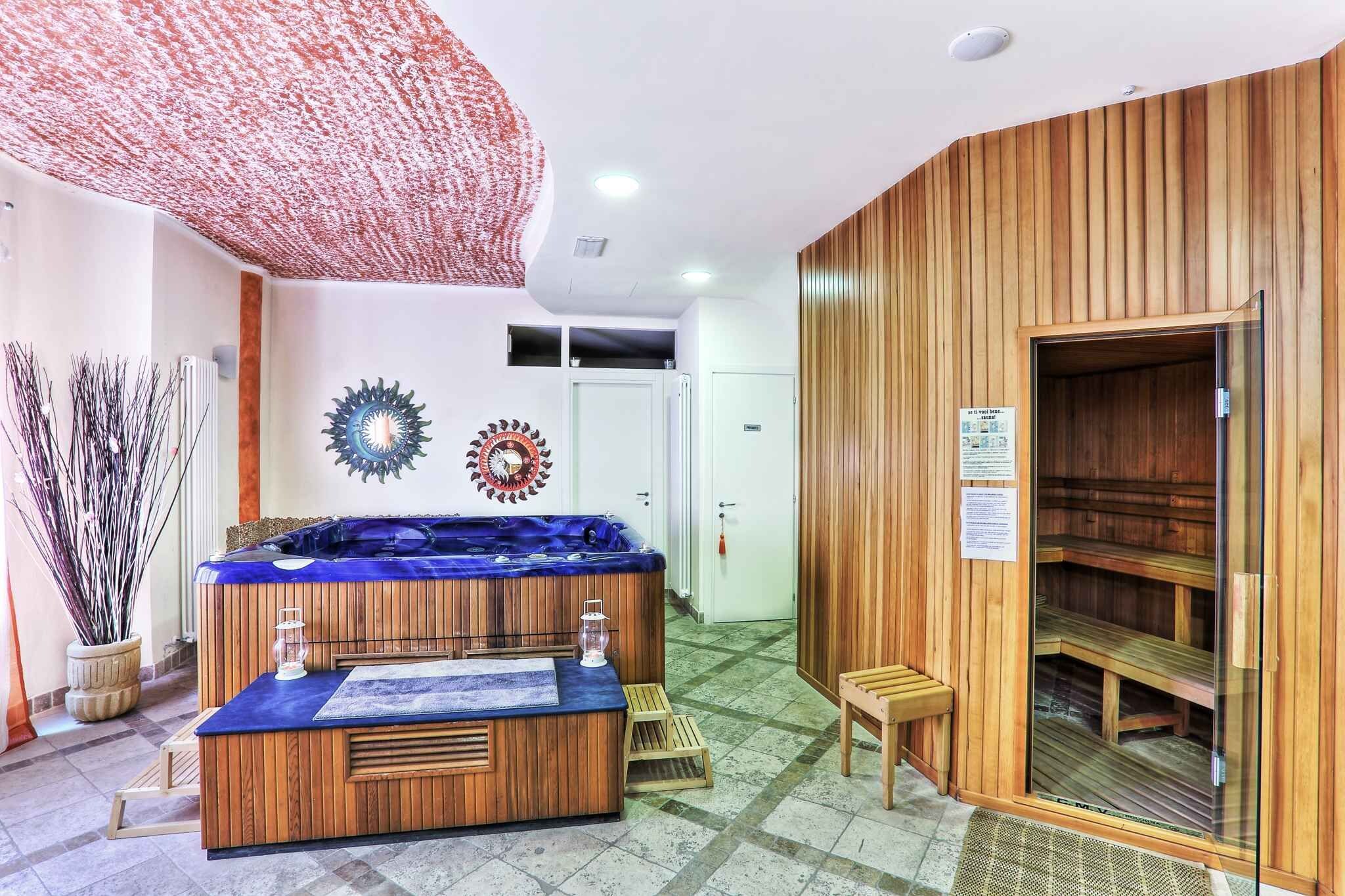 Ein Wellnessbereich mit Holzbadezuber, Sauna und Massageliege.