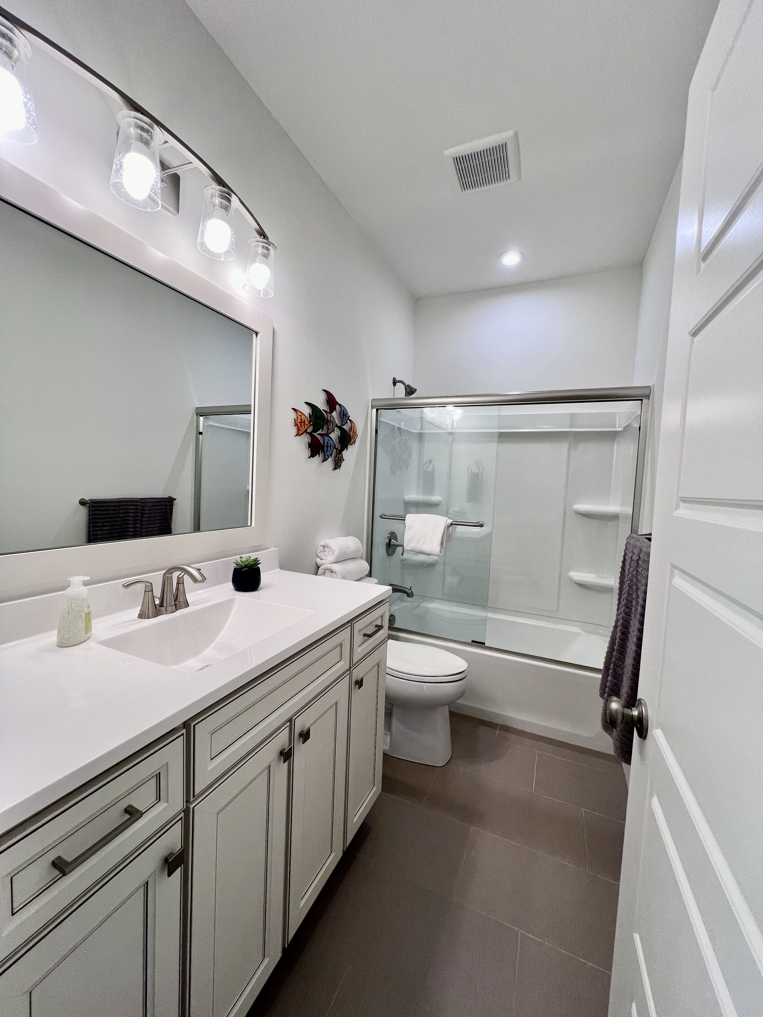 A modern bathroom with a white sink, mirror, and glass shower enclosure.