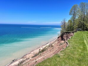Eine Küstenlandschaft mit einer grasbewachsenen Fläche, einem felsigen Felsen und einem klaren, blauen Meer.