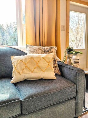 A grey sofa with two decorative pillows, one with a yellow pattern and the other with a floral design.