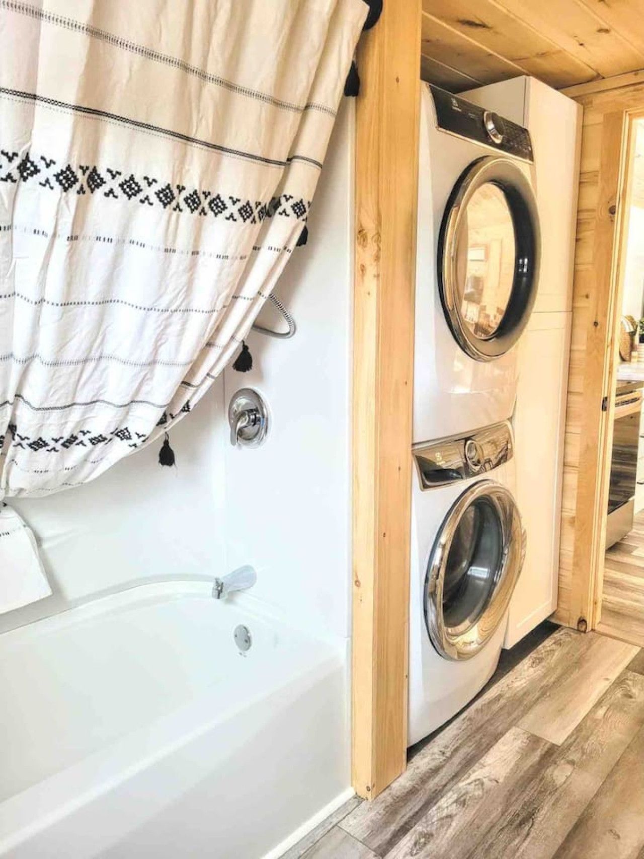 A compact laundry room with a washing machine and a bathtub.