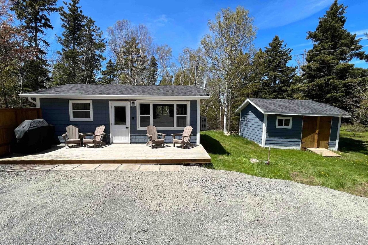 A single-story house with a porch, a small attached garage, and a gravel driveway.