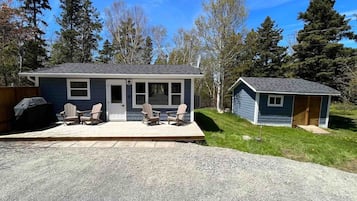A single-story house with a porch, a small attached garage, and a gravel driveway.
