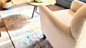 Een gezellige woonkamer met een bank, een aan de muur bevestigde televisie en een kleine ronde tafel met een plant.