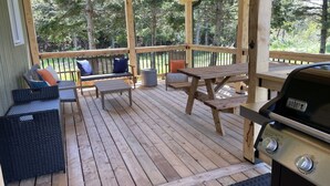A wooden deck with outdoor furniture, including a grill and seating areas. - Chalet Gedouque, a tranquille retreat located on the Cabot Trail with waterfront views (Chéticamp)