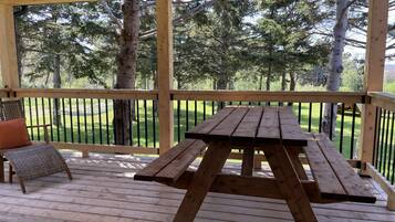 Eine Holzterrasse mit Picknicktisch und Korbstuhl.