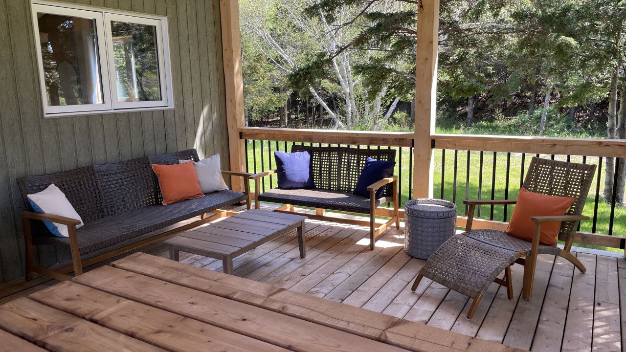 A wooden deck with a sofa, chairs, and a table.