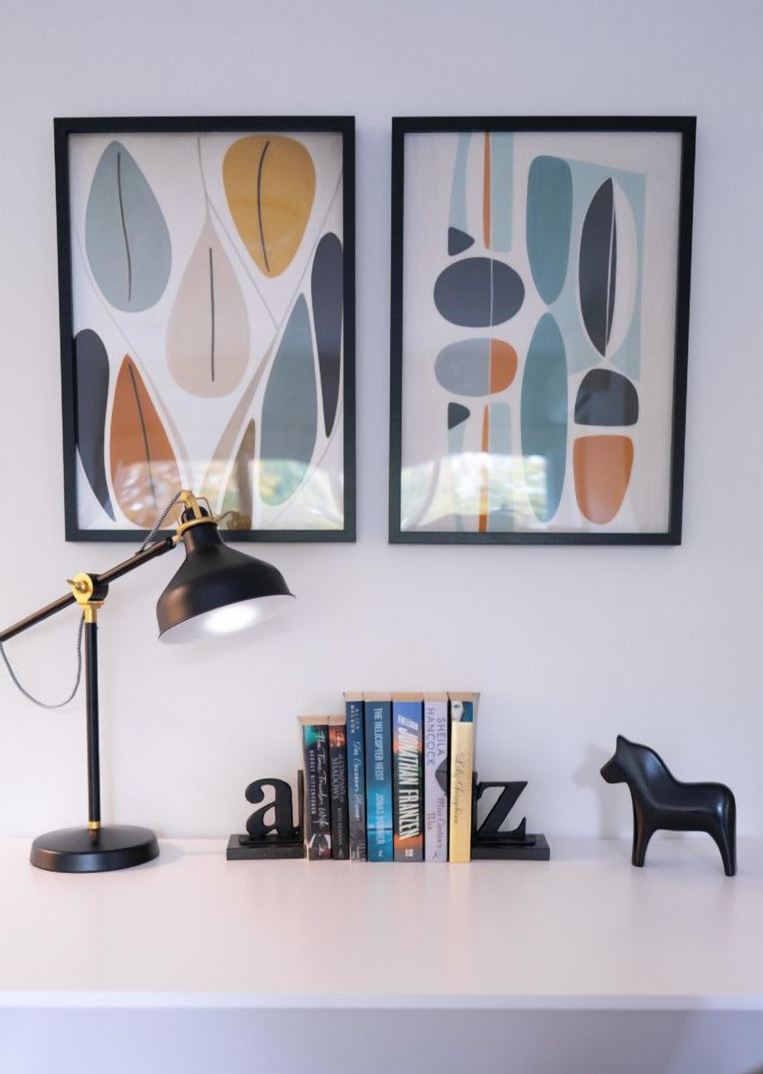 A desk with a black desk lamp, a black horse-shaped sculpture, and a bookshelf with books.