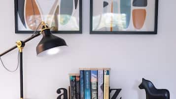 A desk with a black desk lamp, a black horse-shaped sculpture, and a bookshelf with books.