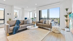 Una sala de estar moderna con dos sofás, una mesa de centro y un amplio ventanal con vista al mar.