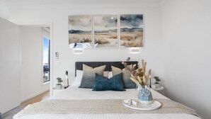 Un dormitorio con una cama grande, vistas al exterior y un cuadro sobre la cama.