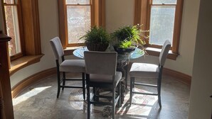 Un comedor con una mesa redonda, cuatro sillas y dos macetas.