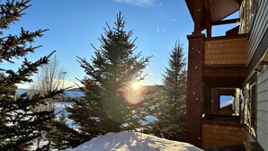 A snow-covered landscape with a building featuring a wooden exterior and a visible staircase leading to a door. - First Tracks 2br 2bath Steamboat Heaven (Steamboat Springs)