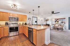 A modern kitchen with wooden cabinets, stainless steel appliances, and a central island. - Steamboat 2 BR Ski Retreat - Gondola, Pool, Hot Tubs, & Mountain Views (Steamboat Springs)