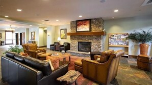 A spacious lobby with leather sofas, a stone fireplace, and a bookshelf. - First Tracks 2br 2bath Steamboat Heaven (Steamboat Springs)