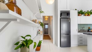 A modern kitchen with white cabinetry, a stainless steel refrigerator, and various potted plants. - Grey Lynn Villa - Short Walk to Ponsonby Central (Auckland)