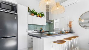 A modern kitchen with a stainless steel refrigerator, white cabinetry, a central island with bar stools, and pendant lighting. - Grey Lynn Villa - Short Walk to Ponsonby Central (Auckland)