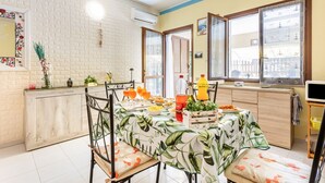 A dining area with a table set for four, a kitchen counter, and a view through a window. - GuestHost - Bright 62sqm apartment, ideal for 3 people, located on the ground floor of a building WITHOUT a lift (two flights of stairs to access it).The accommodation is located in the La Collina residence, in Villasimius, in about 13 minutes by car y (Villasimius)