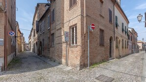 Calle empedrada flanqueada por edificios históricos de ladrillo, con una señal de prohibido el paso y un paso de peatones.