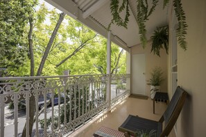A balcony with a white railing, a bench, and hanging plants. - Where Barbie Lives by Glass Et Cetera (Chippendale)