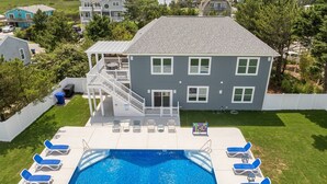 Une maison à deux étages avec une piscine, un patio couvert et une vue sur un lac.