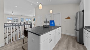 Une cuisine moderne dotée d’un îlot central, de meubles blancs et d’appareils électroménagers en acier inoxydable.