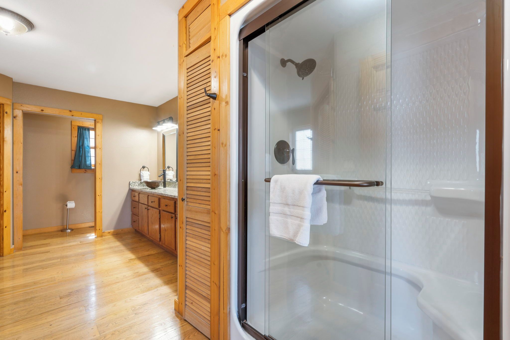 Un baño con cabina de ducha de vidrio, armarios de madera y un toallero visible.