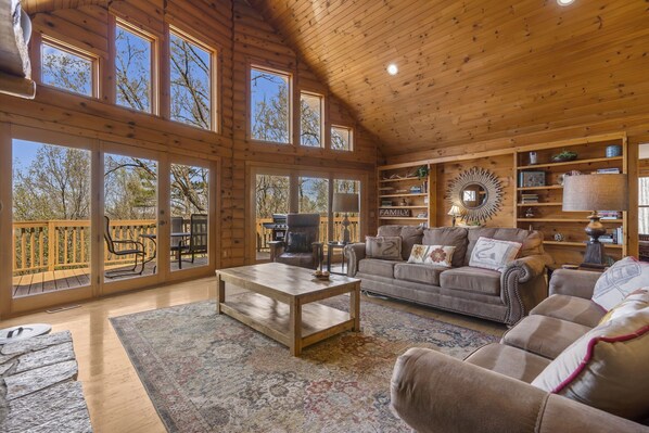 A spacious living room with large windows, a fireplace, and a cozy seating area. - Rustic Lakeview Cabin Escape featuring Billiards, Free Daily Attraction Tickets & Close to Big Cedar (Ridgedale)