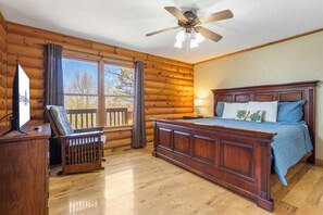 A log cabin bedroom with a wooden bed, a desk, and a television. - Rustic Lakeview Cabin Escape featuring Billiards, Free Daily Attraction Tickets & Close to Big Cedar (Ridgedale)