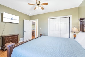 A bedroom with a bed, a ceiling fan, a dresser, a lamp, and a door leading to another room. - Rustic Lakeview Cabin Escape featuring Billiards, Free Daily Attraction Tickets & Close to Big Cedar (Ridgedale)