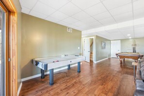 Une pièce spacieuse équipée d’une table de billard, d’une table de jeu de flipper et d’un canapé.