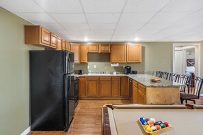 A kitchen with wooden cabinets, a black refrigerator, a granite countertop, and a pool table with billiard balls. - Rustic Lakeview Cabin Escape featuring Billiards, Free Daily Attraction Tickets & Close to Big Cedar (Ridgedale)