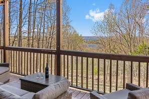 A covered outdoor seating area with a view of a forest and a body of water.
