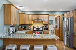 A kitchen with wooden cabinets, granite countertops, a stainless steel refrigerator, and a built-in oven.