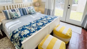 A bedroom with a bed, bedside table, lamp, and a view of the outside. - YOUPON DRIVE (Galveston)