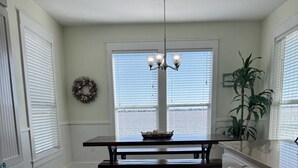 A kitchen with a wooden floor, white cabinetry, a dining table, and a view of the water through large windows. - Serenity on Salt Lake (Rockport)
