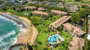 Een resort met strandwoningen, een zwembad en weelderige begroeiing.
